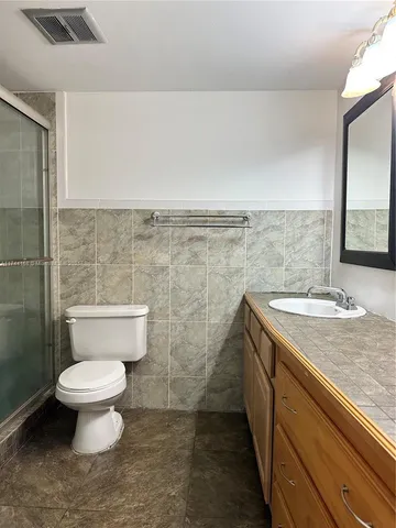 a bathroom with a granite countertop toilet and a sink