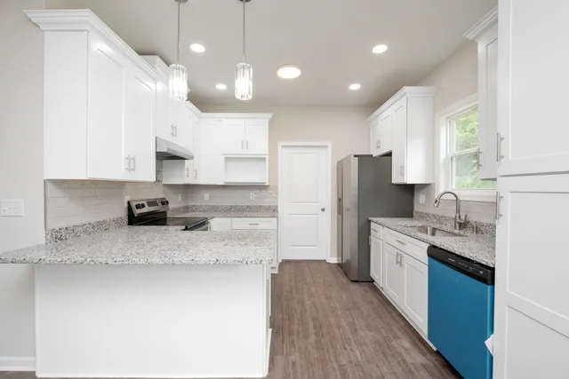 a large kitchen with stainless steel appliances kitchen island granite countertop a sink refrigerator and cabinets