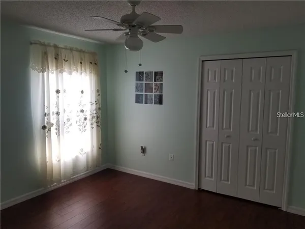 an empty room with wooden floor fan and windows