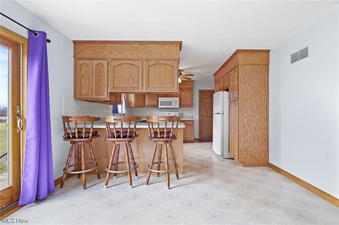 411 Adario West Road Shiloh, OH 44878 - Photo 6 of 35 Kitchen with white appliances, a breakfast bar, a wealth of natural light, and ceiling fan