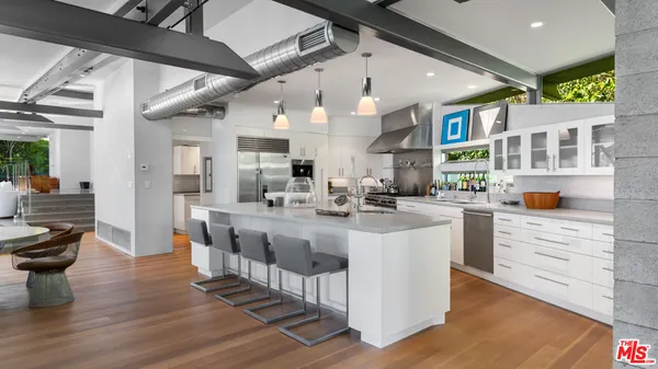 a kitchen with a sink stainless steel appliances lots of counter top space and furniture