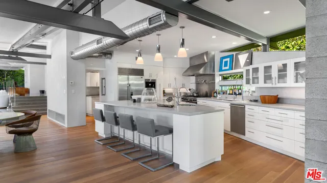 a kitchen with a sink stainless steel appliances lots of counter top space and furniture