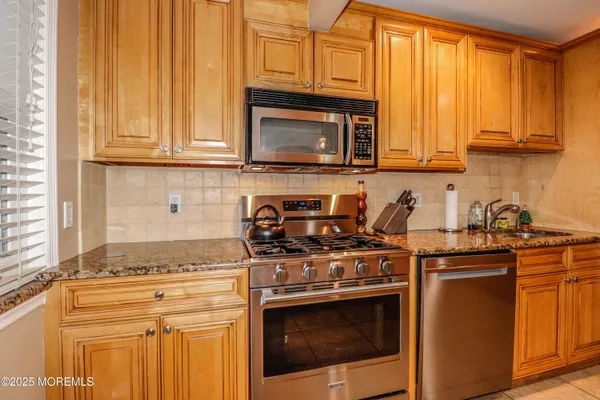 a kitchen with stainless steel appliances granite countertop a refrigerator stove and sink