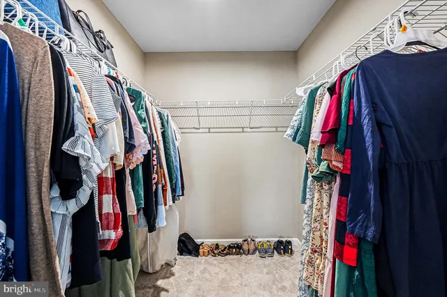 a view of walk in closet with clothes and shoes