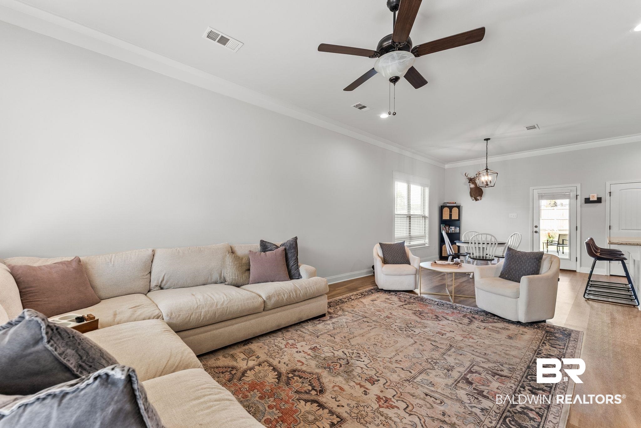 10745 Brodick Loop Daphne, AL 36527 - Photo 7 of 39 Living room featuring a ceiling fan, crown molding, wood finished floors, and hanging lights