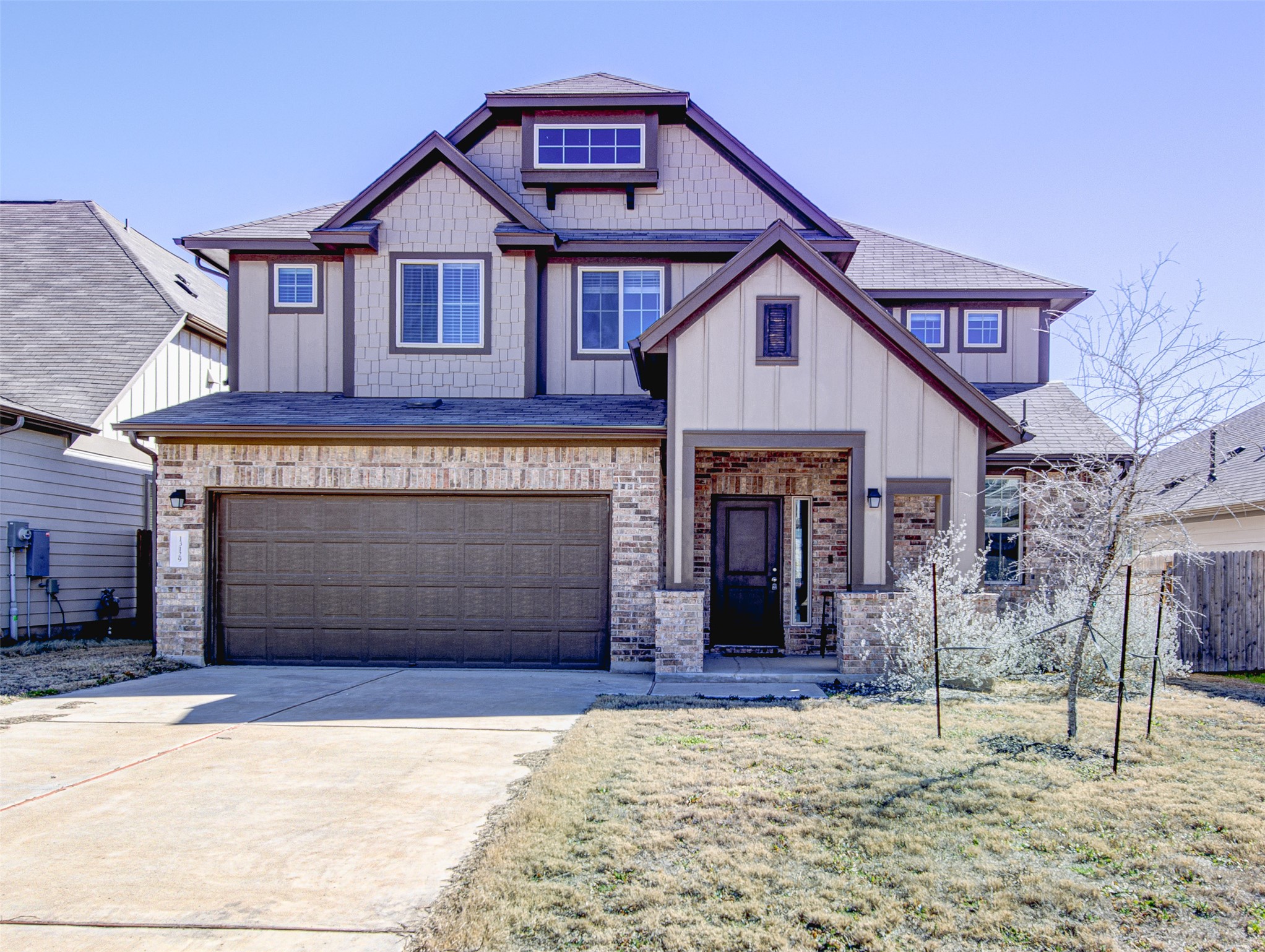 Craftsman-style home featuring board and batten siding, roof with shingles, concrete driveway, an attached garage, and brick siding