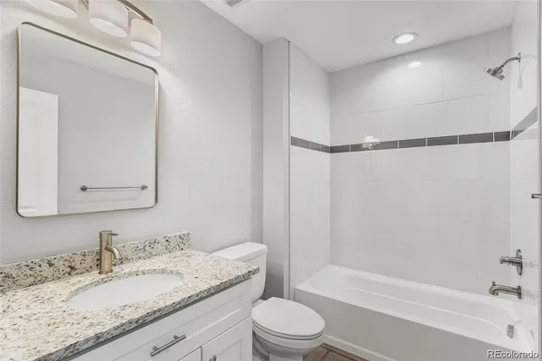 a bathroom with a granite countertop sink toilet and shower