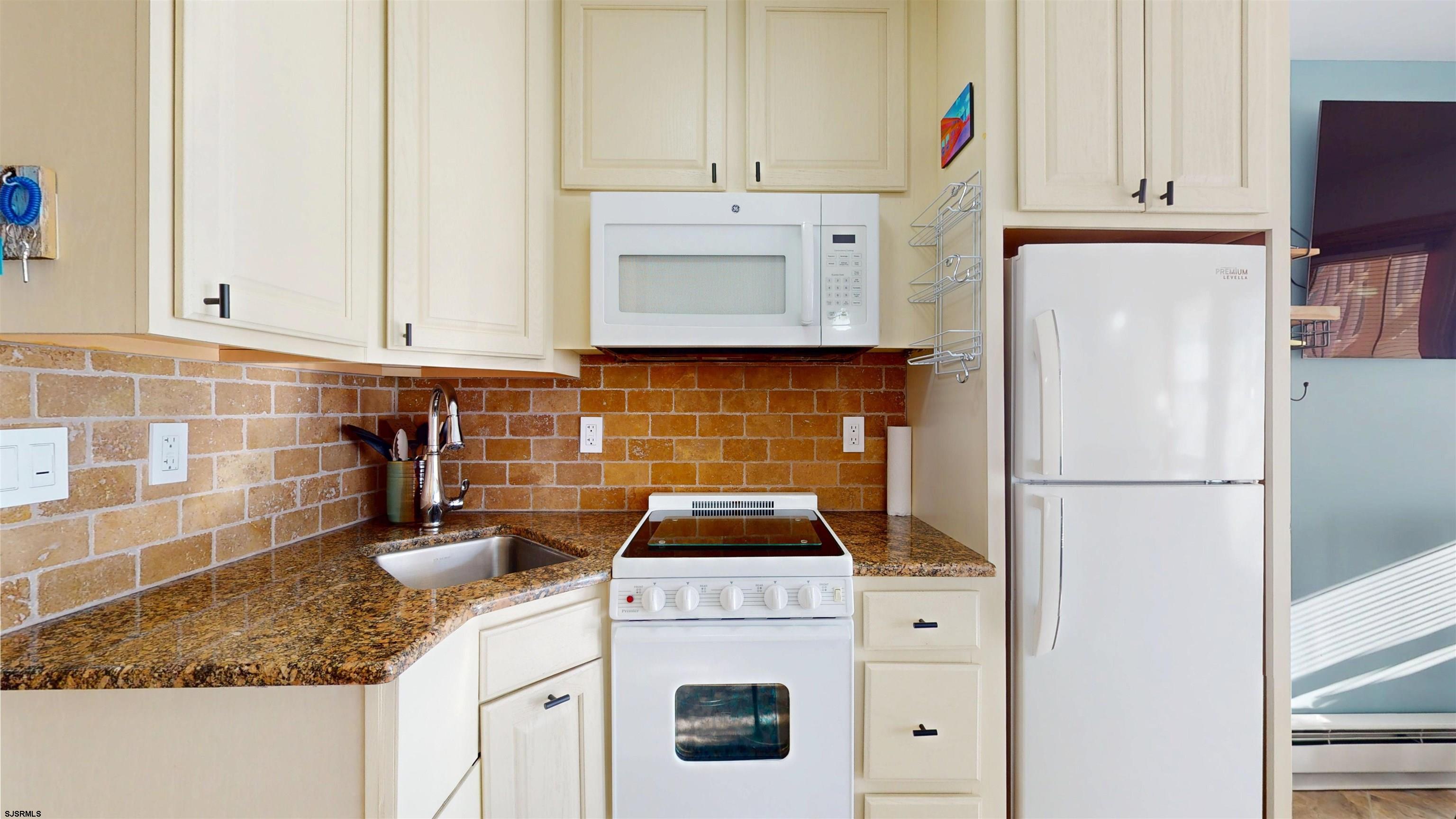 719 East Brigantine Avenue, Unit 1A Brigantine, NJ 08203 - Photo 14 of 37 a kitchen with granite countertop white cabinets and white appliances