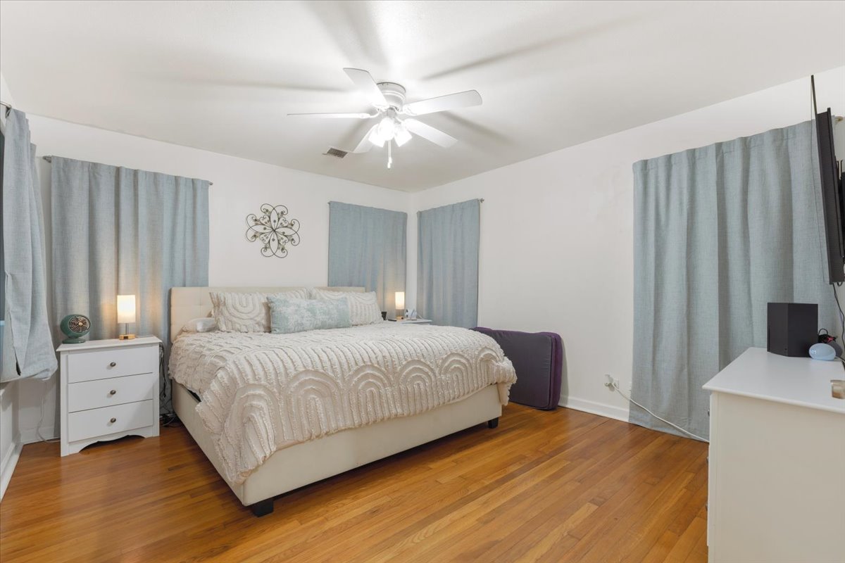 607 Short Street Smithville, TX 78957 - Photo 12 of 31 Expansive sleeping quarters featuring wood-finish flooring, white walls, and a ceiling fan with integrated lighting
