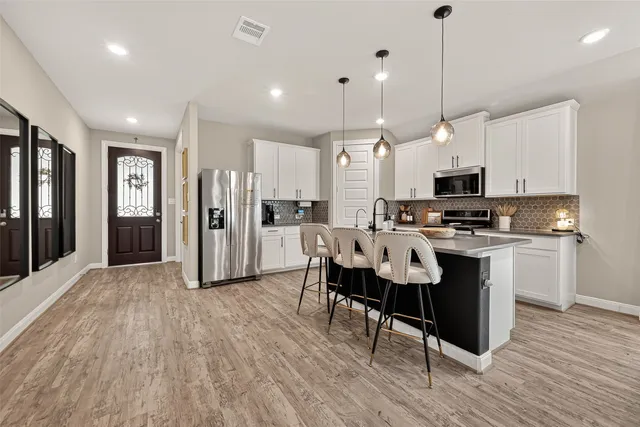 a kitchen with stainless steel appliances granite countertop a sink a stove a refrigerator cabinets and chairs