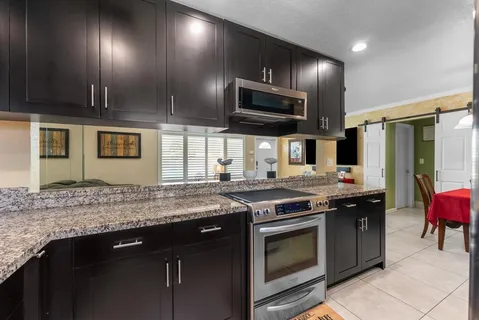 a kitchen with stainless steel appliances granite countertop a stove a sink and a microwave