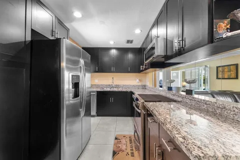 a large kitchen with granite countertop a large counter top stainless steel appliances and cabinets