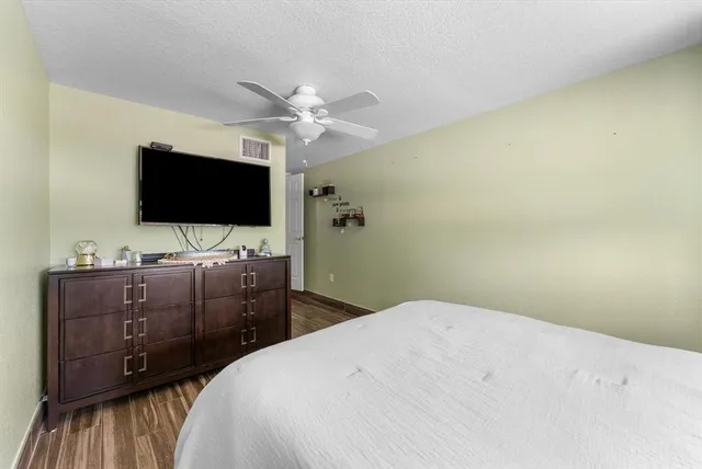 a bedroom with a bed and a flat tv screen on dresser