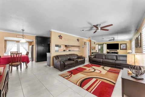 a living room with furniture a flat screen tv and kitchen view