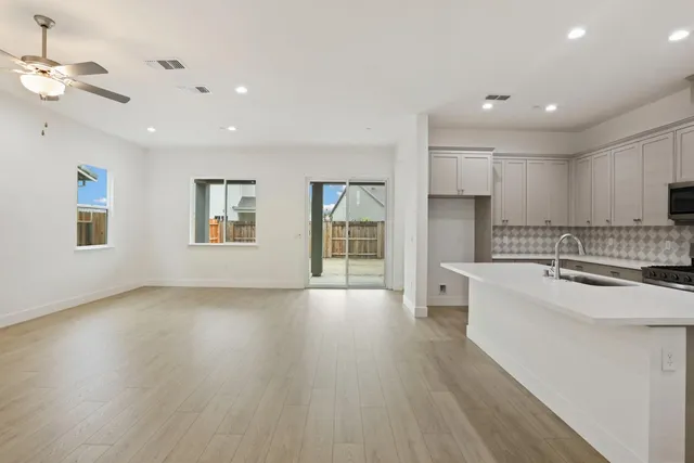 a large kitchen with stainless steel appliances a large counter top a sink a refrigerator and a window