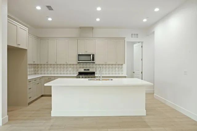 a kitchen with kitchen island a white counter top space cabinets and stainless steel appliances
