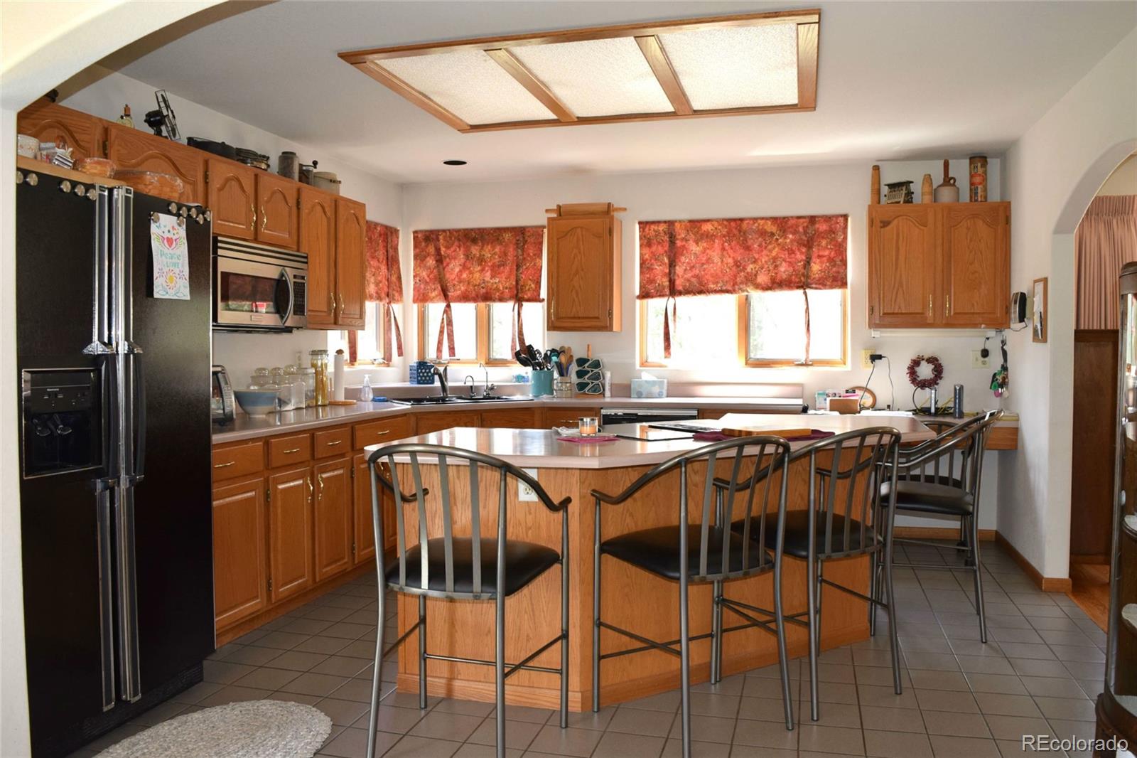 631 Old Corral Road Bailey, CO 80421 - Photo 7 of 35 a kitchen with stainless steel appliances granite countertop a stove a refrigerator a kitchen island and chairs in it