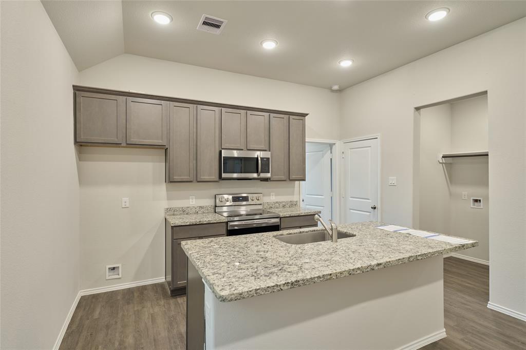 9992 Calendar Street Willis, TX 77318 - Photo 4 of 25 a kitchen with kitchen island granite countertop a sink stove and refrigerator