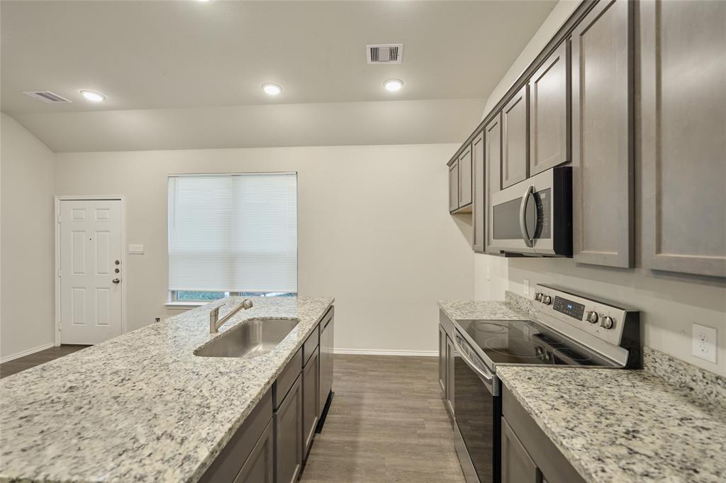 9992 Calendar Street Willis, TX 77318 - Photo 5 of 25 a kitchen with stainless steel appliances granite countertop a sink stove and refrigerator