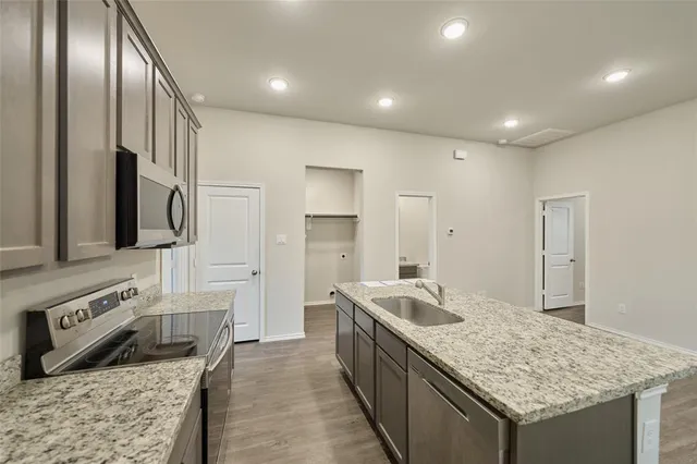 a large kitchen with stainless steel appliances granite countertop a lot of counter space and wooden floor