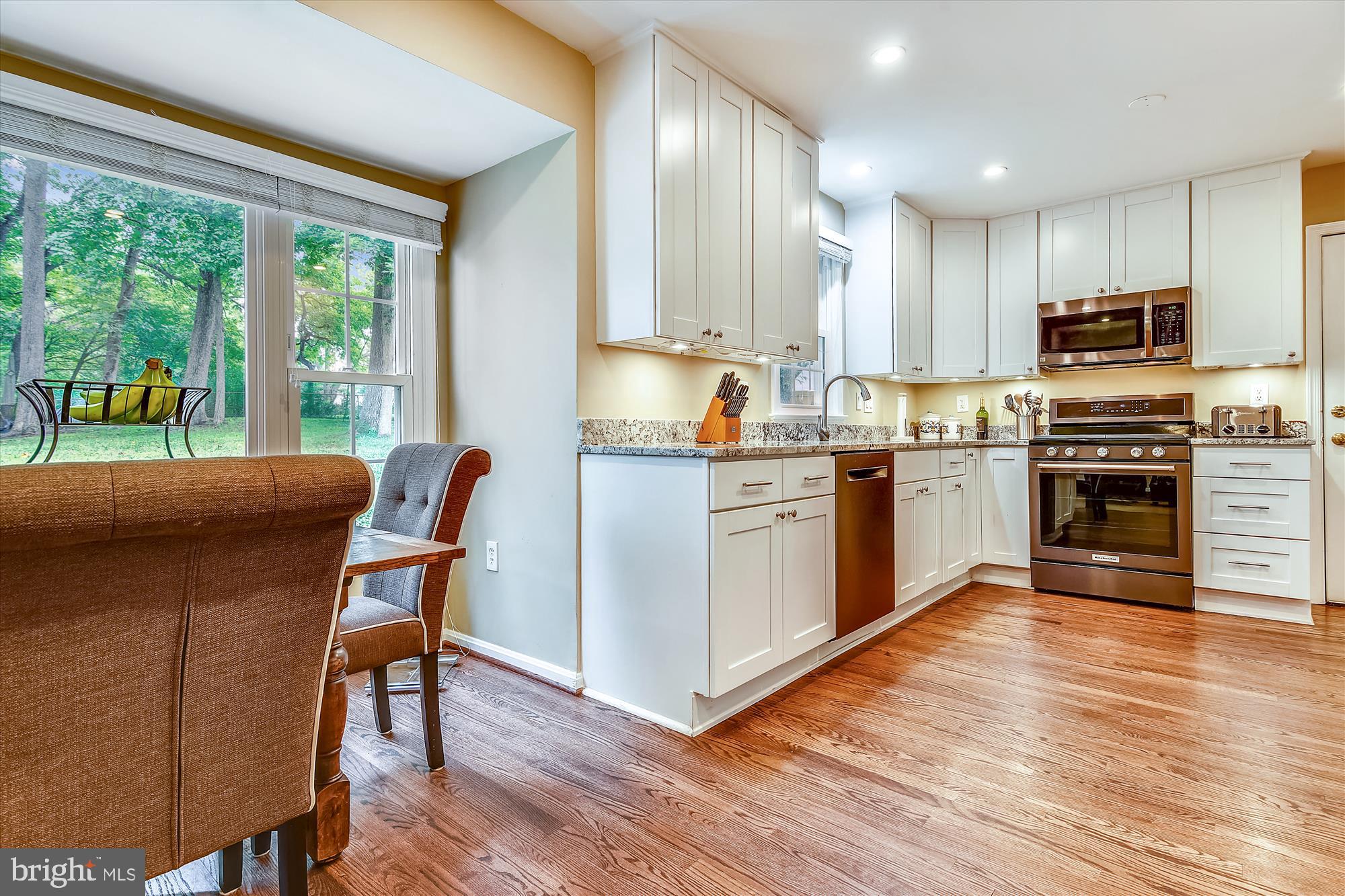 13621 Middlevale Lane Silver Spring, MD 20906 - Photo 8 of 25 a kitchen with stainless steel appliances granite countertop a stove top oven a sink dishwasher a dining table and chairs with wooden floor