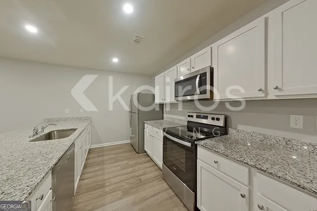 a kitchen with granite countertop stainless steel appliances a sink stove top oven and cabinets