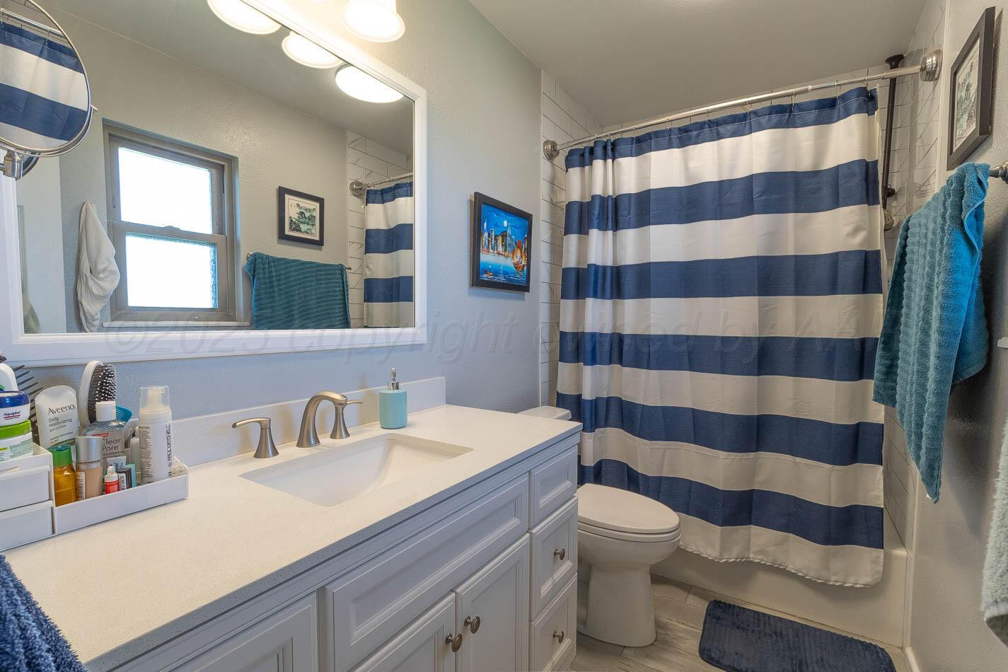 121 Houston Street Borger, TX 79007 - Photo 14 of 21 a bathroom with a sink a toilet a large mirror and shower curtain