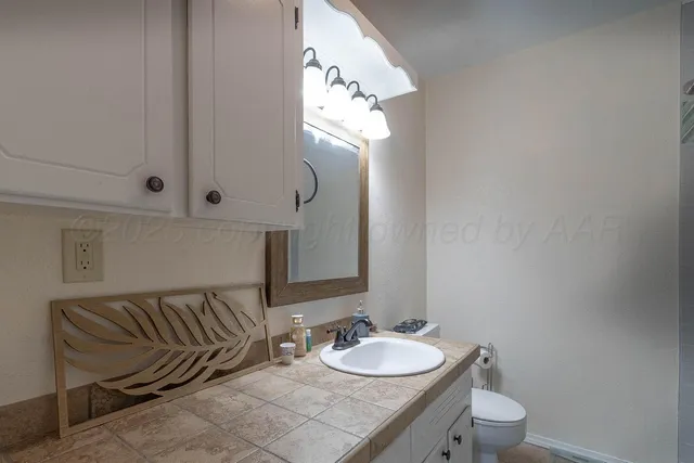 a bathroom with a granite countertop sink and a mirror with toilet