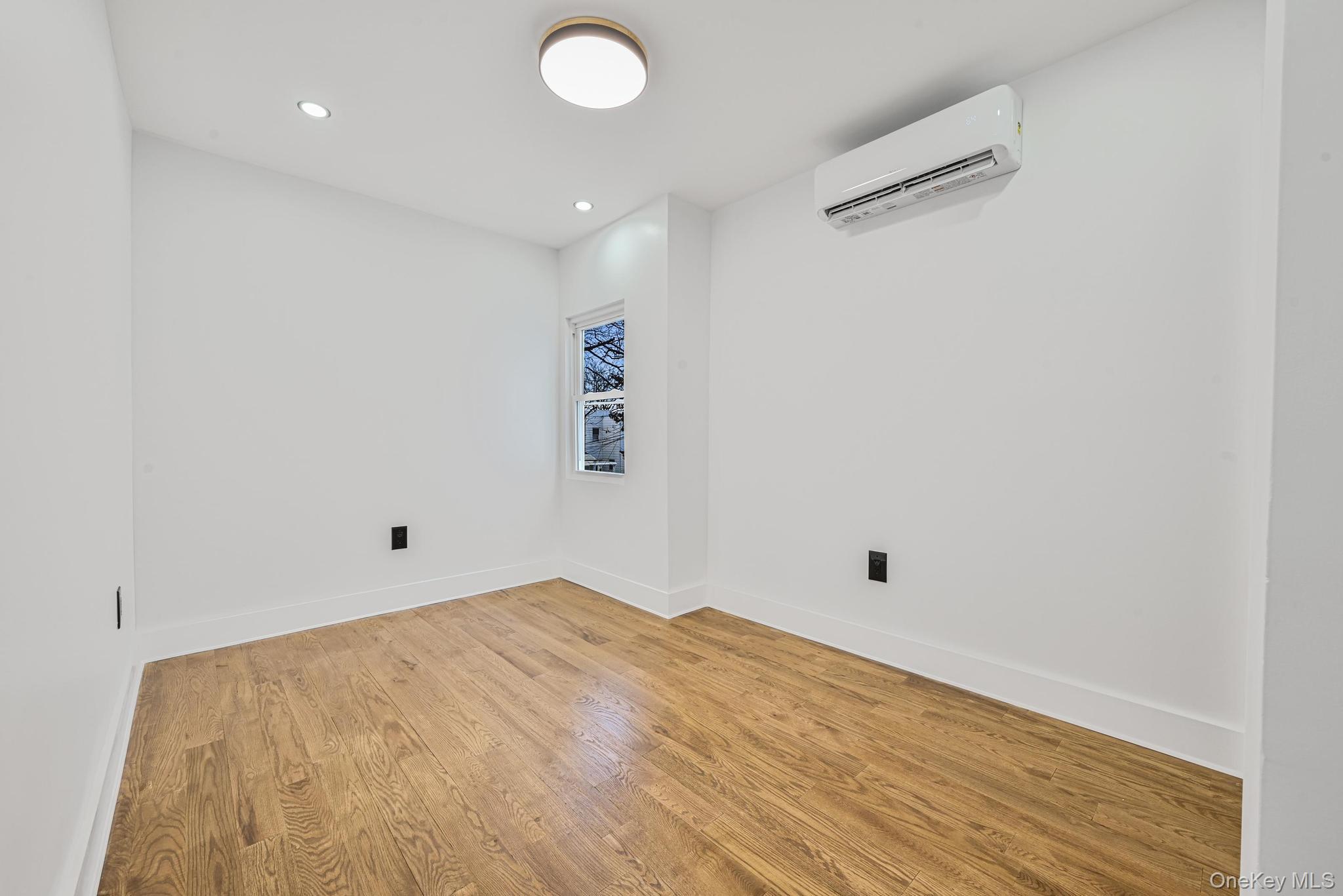 92-43 76th Street Queens, NY 11421 - Photo 17 of 20 Spare room with wood finished floors, a wall unit AC, and recessed lighting