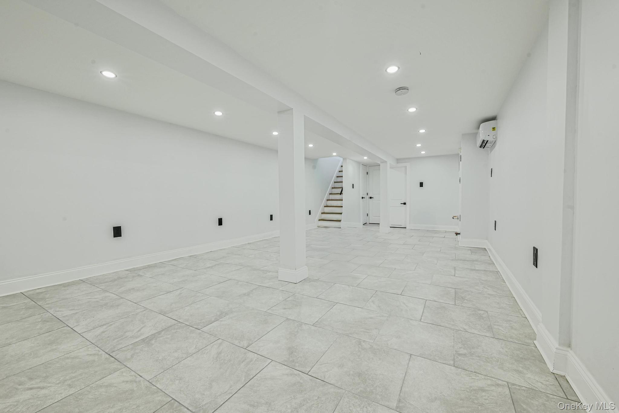 92-43 76th Street Queens, NY 11421 - Photo 19 of 20 Finished below grade area featuring stairway, recessed lighting, and a wall mounted AC