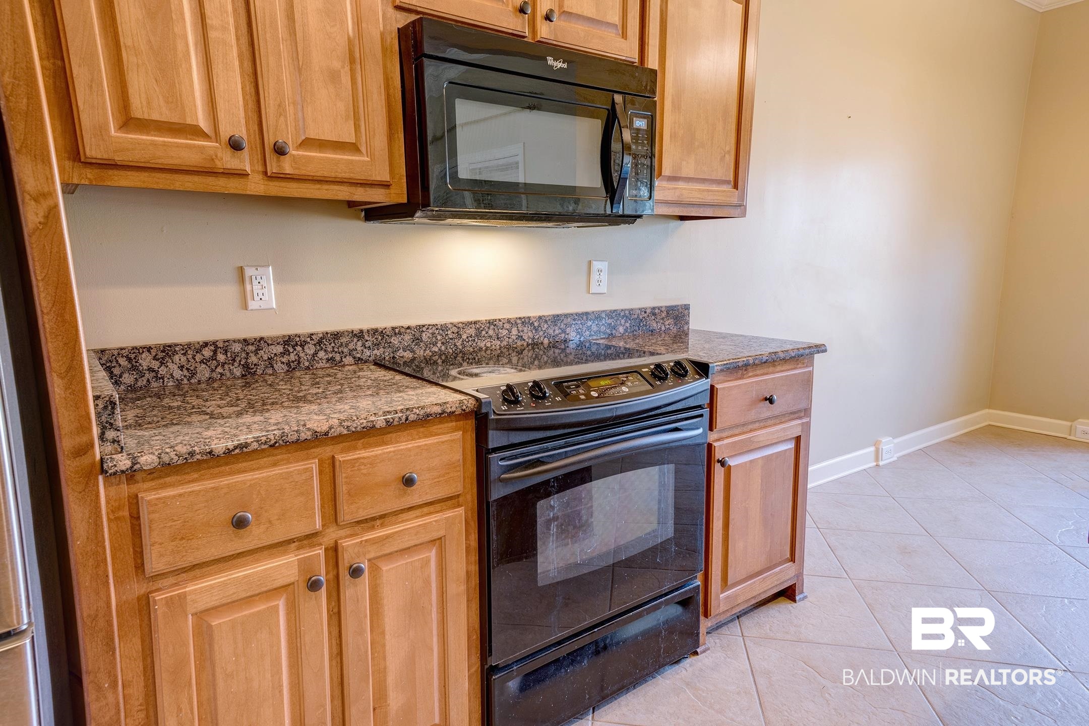 9421 Collier Loop Daphne, AL 36526 - Photo 14 of 31 Kitchen featuring black appliances, light tile patterned floors, brown cabinets, and dark stone counters