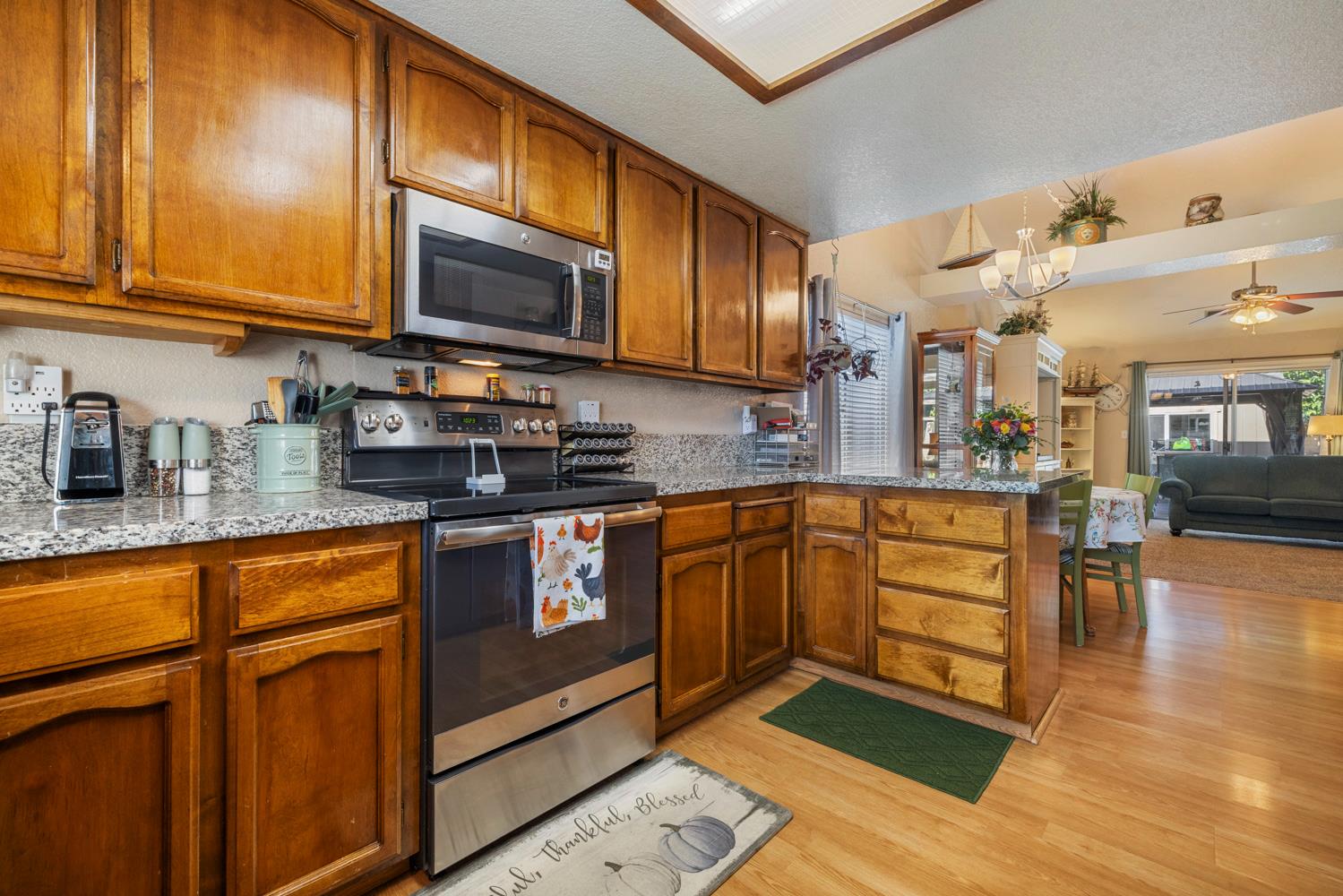 1121 Raymond Drive Modesto, CA 95351 - Photo 13 of 44 a kitchen with stainless steel appliances granite countertop wooden cabinets a sink and dishwasher a stove with wooden floor