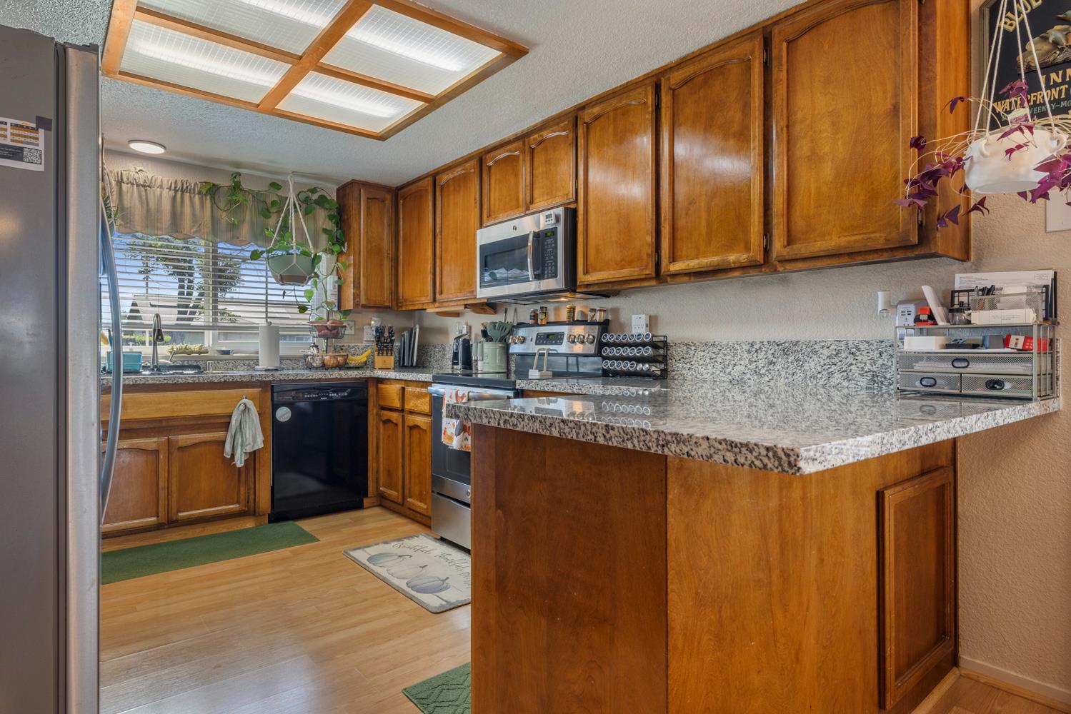 1121 Raymond Drive Modesto, CA 95351 - Photo 10 of 44 a kitchen with stainless steel appliances granite countertop wooden cabinets a sink and dishwasher