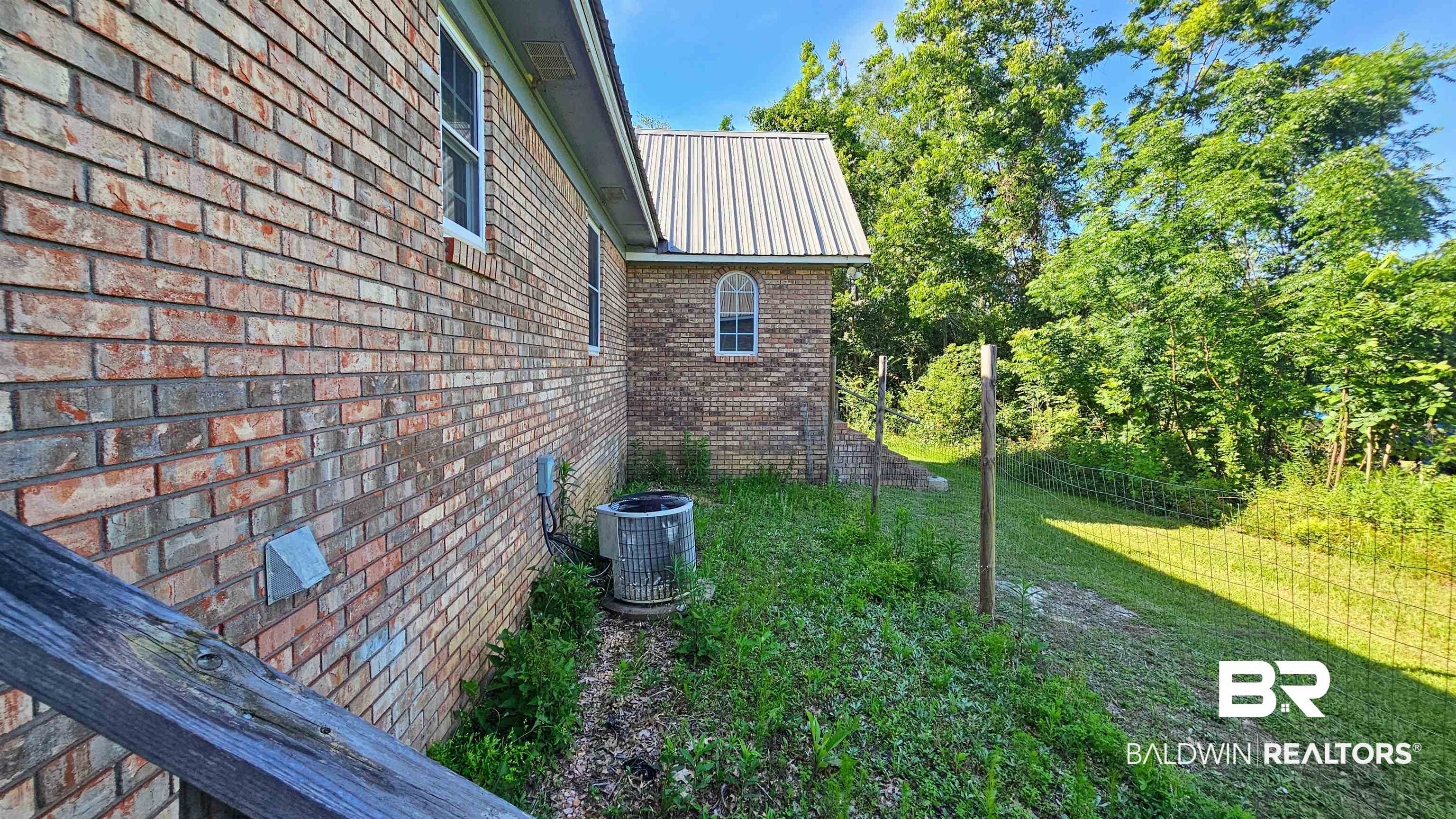 18824 Highway 41 Brewton, AL 36426 - Photo 11 of 40 Brick exterior featuring white-framed windows and a metal roof