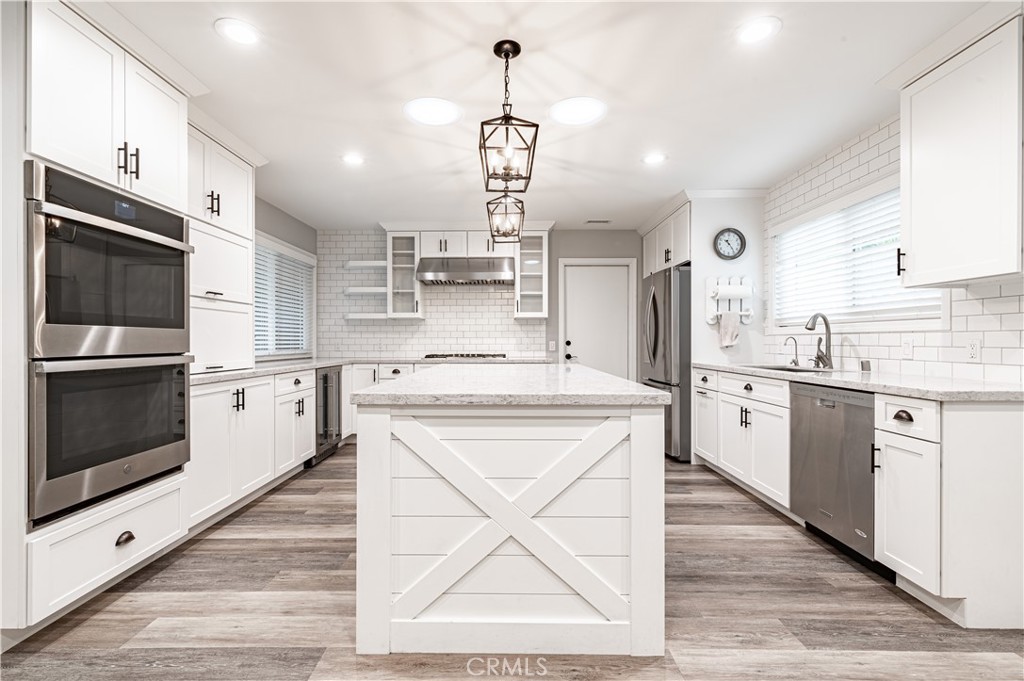 4580 Hazelnut Avenue Seal Beach, CA 90740 - Photo 5 of 34 a kitchen with kitchen island granite countertop a stove top oven a sink dishwasher and white cabinets with wooden floor