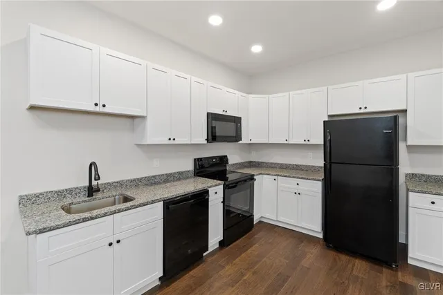 a kitchen with a sink a refrigerator and white cabinets