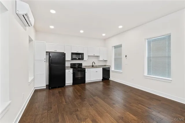 a kitchen with a refrigerator a stove top oven and wooden floor
