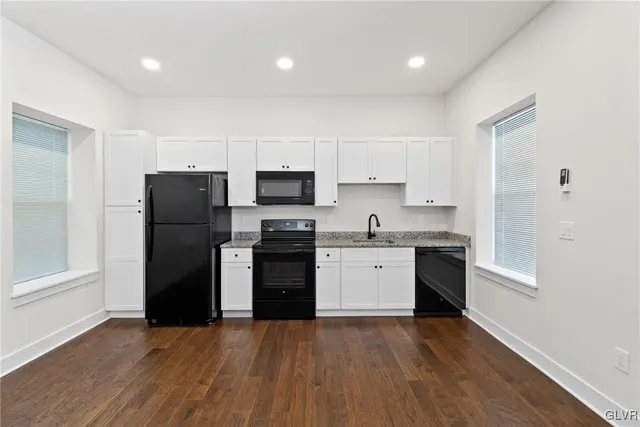 a kitchen with granite countertop white cabinets and stainless steel appliances