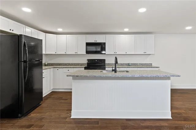 a kitchen with stainless steel appliances granite countertop a stove top oven a refrigerator a sink and a granite counter tops