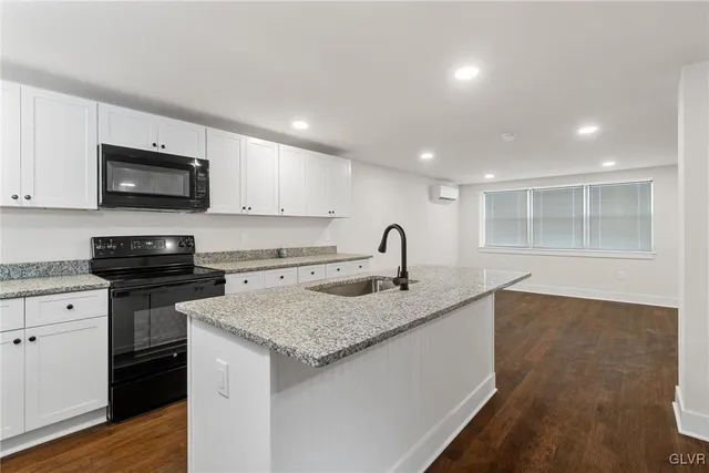 a kitchen with a sink and a stove top oven with wooden floor