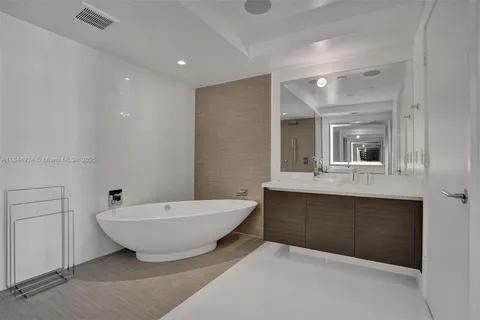 a spacious bathroom with a bathtub sink and mirror