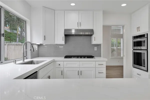 a kitchen with stainless steel appliances granite countertop a sink a stove and a refrigerator