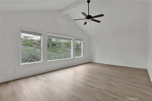an empty room with wooden floor fan and windows