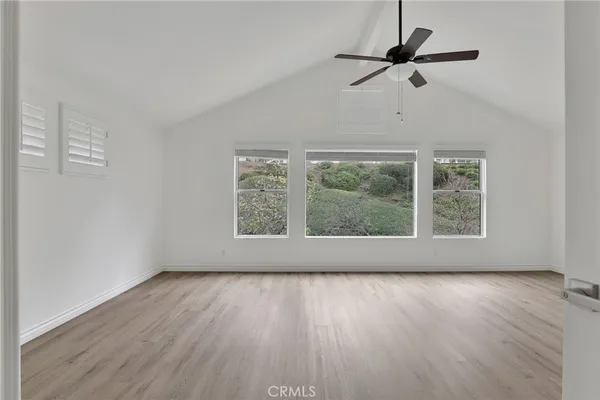 an empty room with wooden floor ceiling fan and window