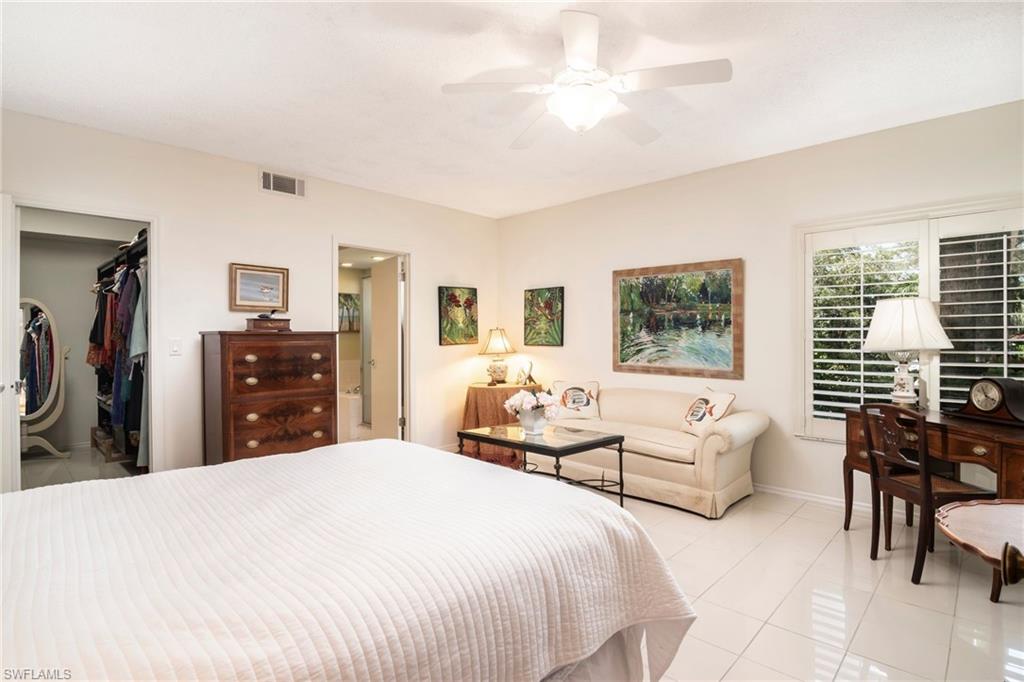 760 Willowbrook Drive, Unit 1202 Naples, FL 34108 - Photo 12 of 28 a bedroom with a large bed and a chandelier