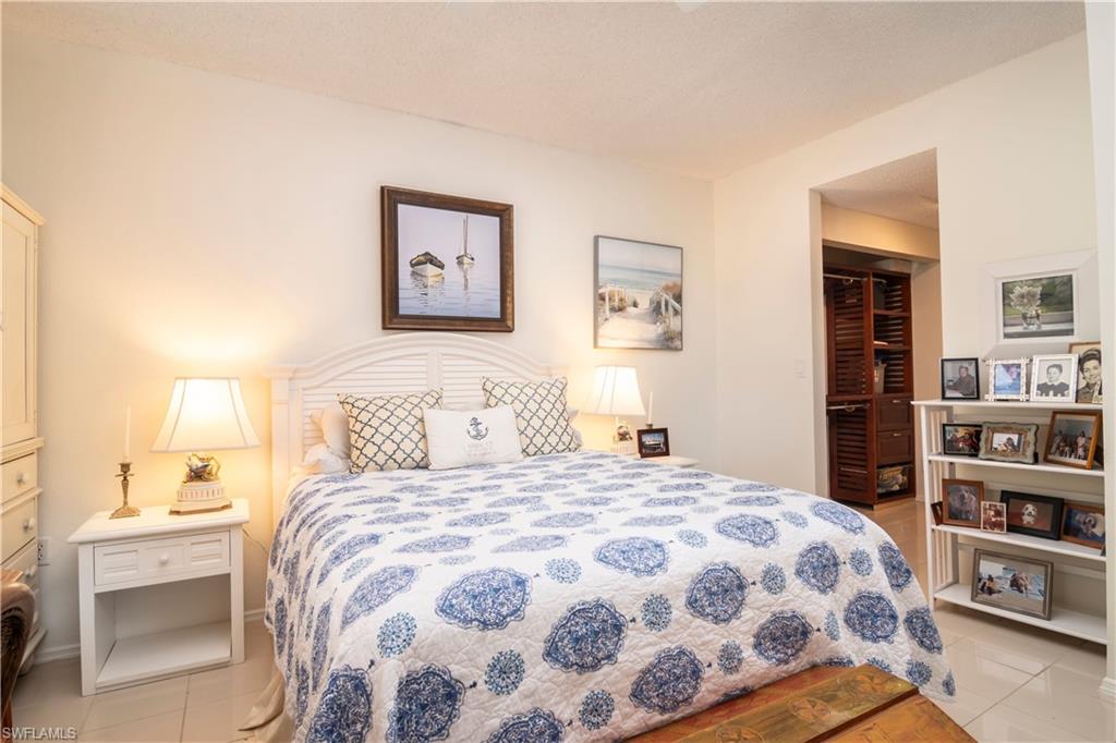 760 Willowbrook Drive, Unit 1202 Naples, FL 34108 - Photo 17 of 28 a bedroom with a bed and a book shelf