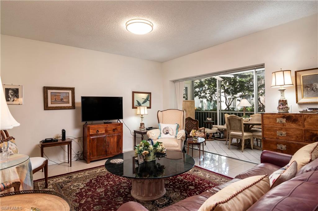 760 Willowbrook Drive, Unit 1202 Naples, FL 34108 - Photo 5 of 28 a living room with furniture fireplace and a large window