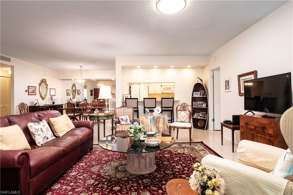 760 Willowbrook Drive, Unit 1202 Naples, FL 34108 - Photo 6 of 28 a living room with furniture potted plant and a flat screen tv