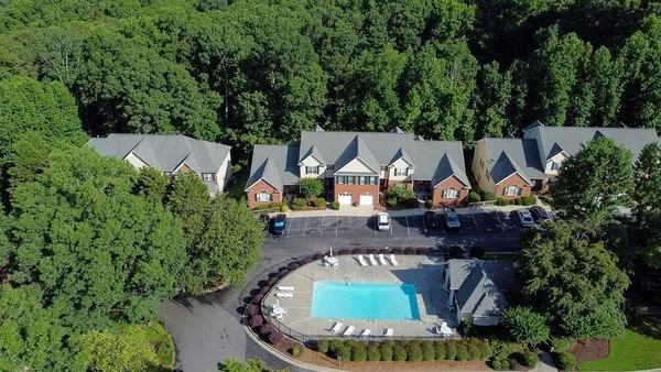an aerial view of a house with outdoor space and trees all around