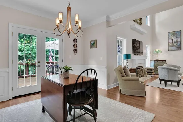 a dining room with wooden floor a chandelier a wooden table and chairs